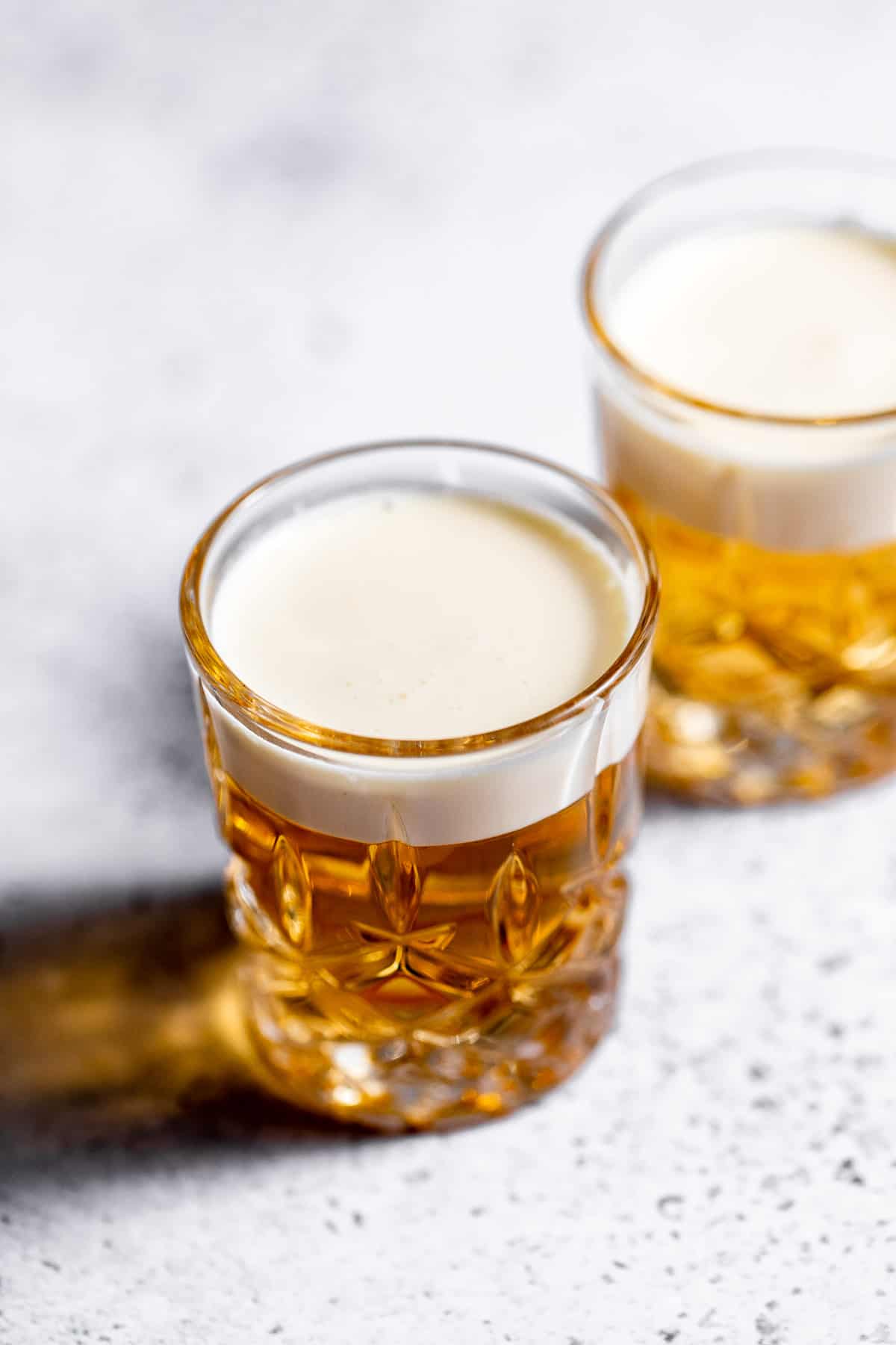 Two layered Mini Beer Shots on marble background with heavy cream topping.