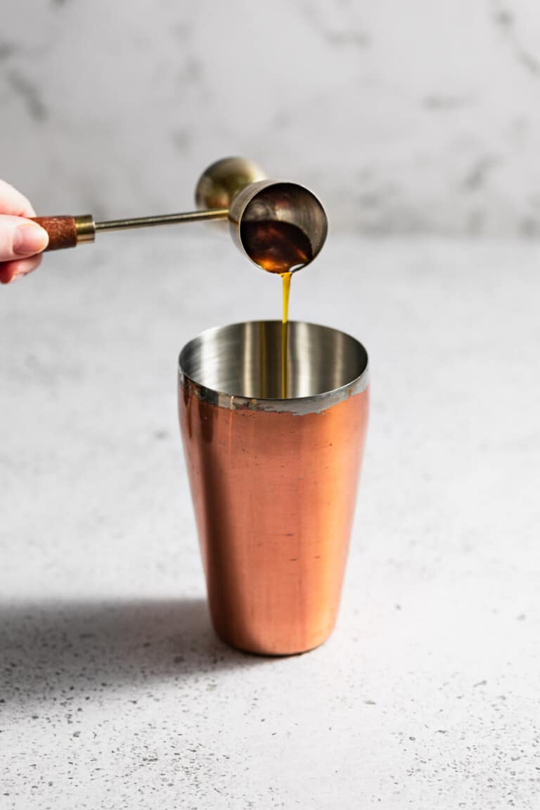 pouring honey syrup into cocktail shaker