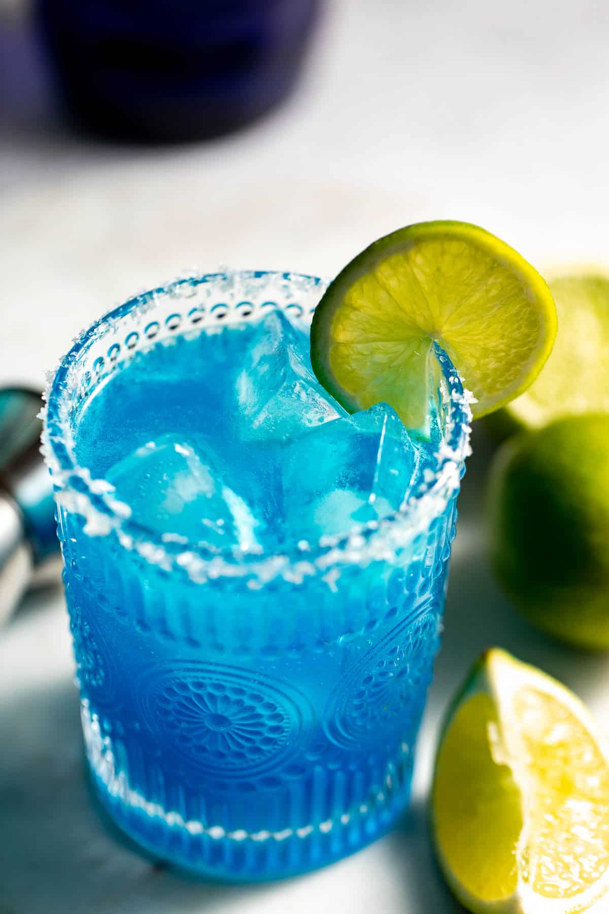 blue cocktail with ice and limes