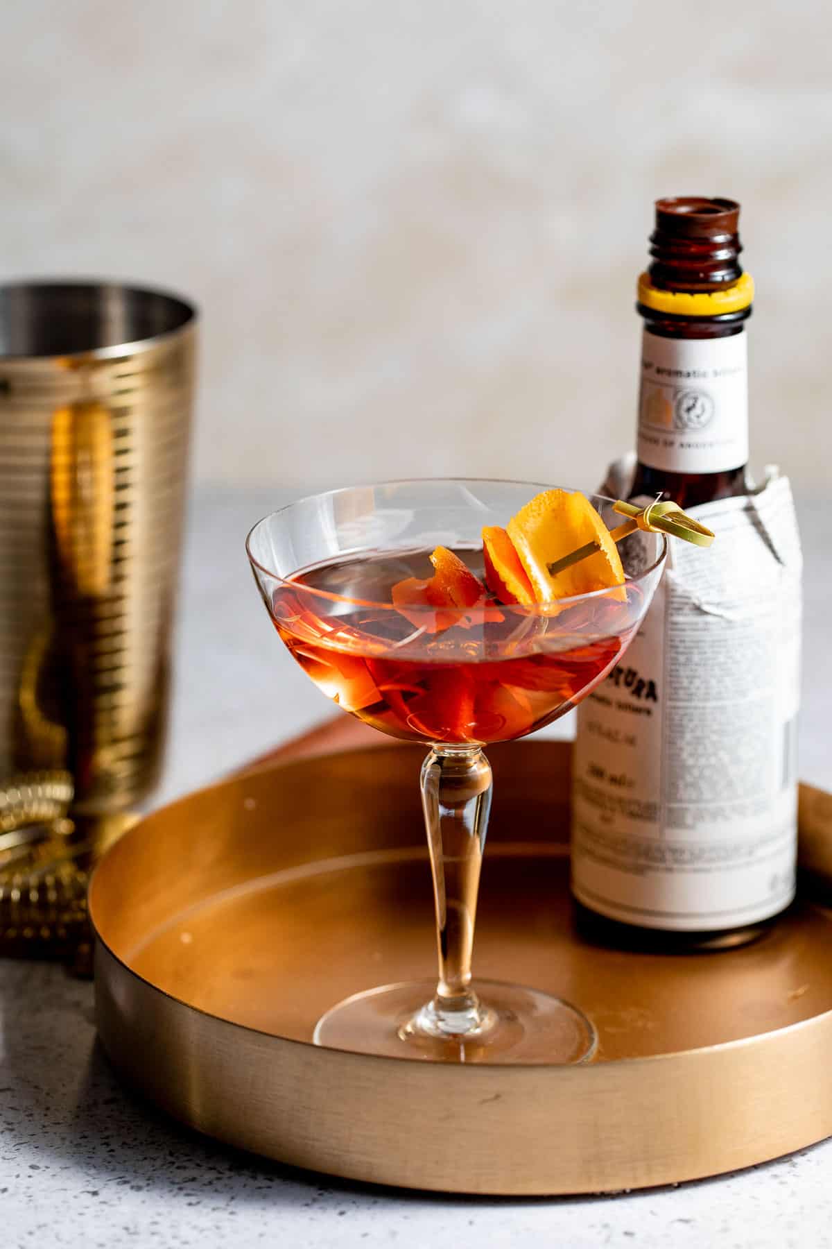 A brandy Manhattan cocktail with an orange zest garnish.