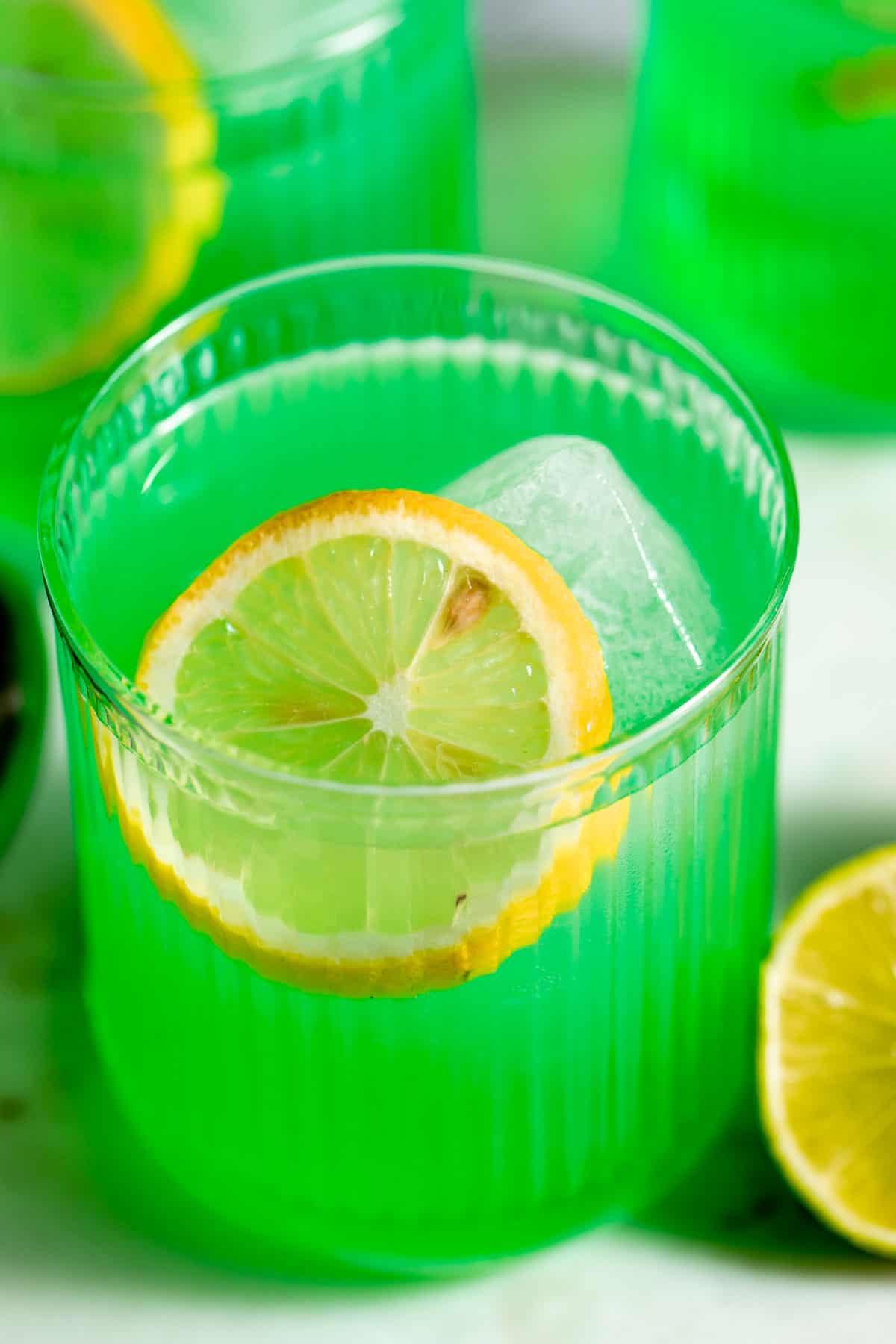 three midori sour cocktails garnished with lemon