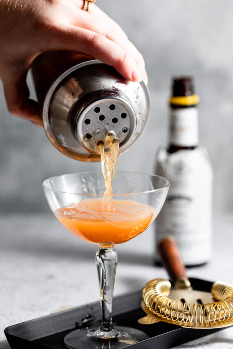 pouring cocktail into coupe glass