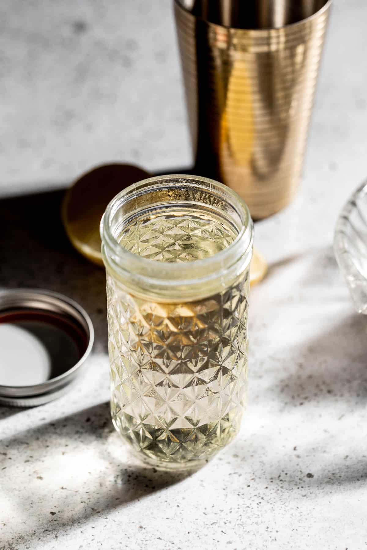 simple syrup in a glass jar with cocktail shaker in the background