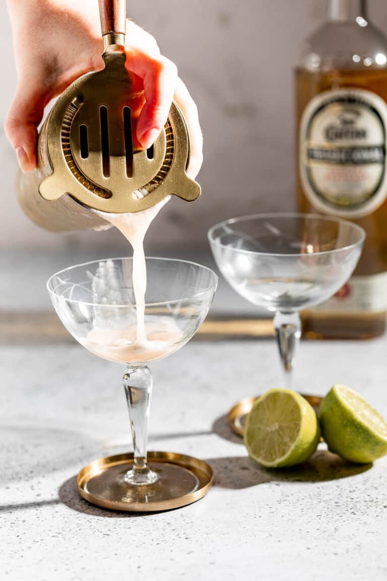 straining tequila sour into glass