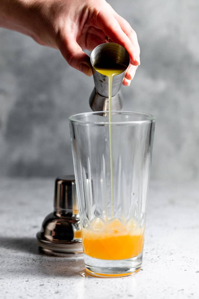 adding pineapple juice to cocktail shaker