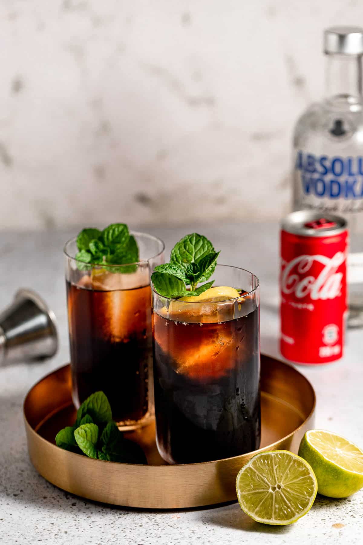 vodka and coke on gold tray with fresh mint and vodka bottle