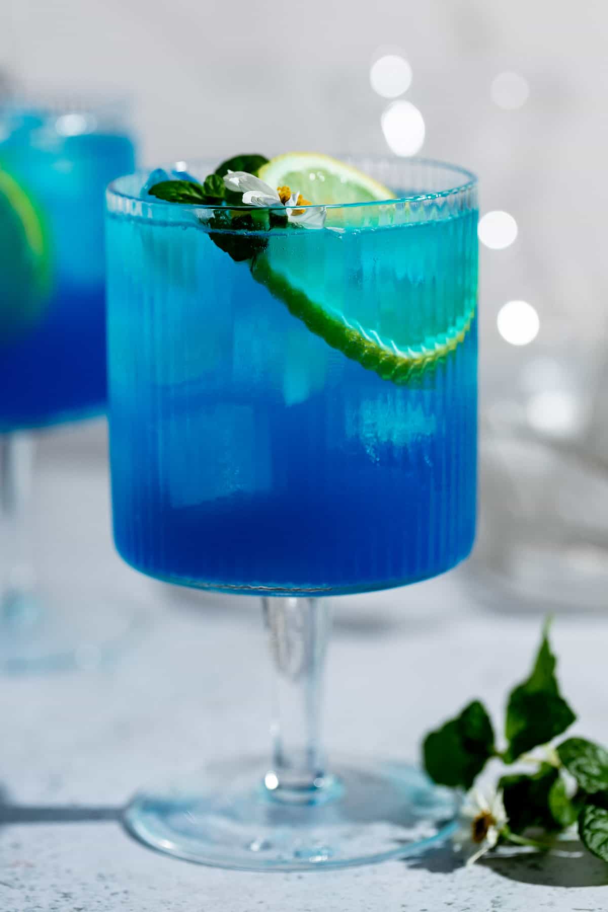 tall blue cocktail with fresh lemon in ribbed glass