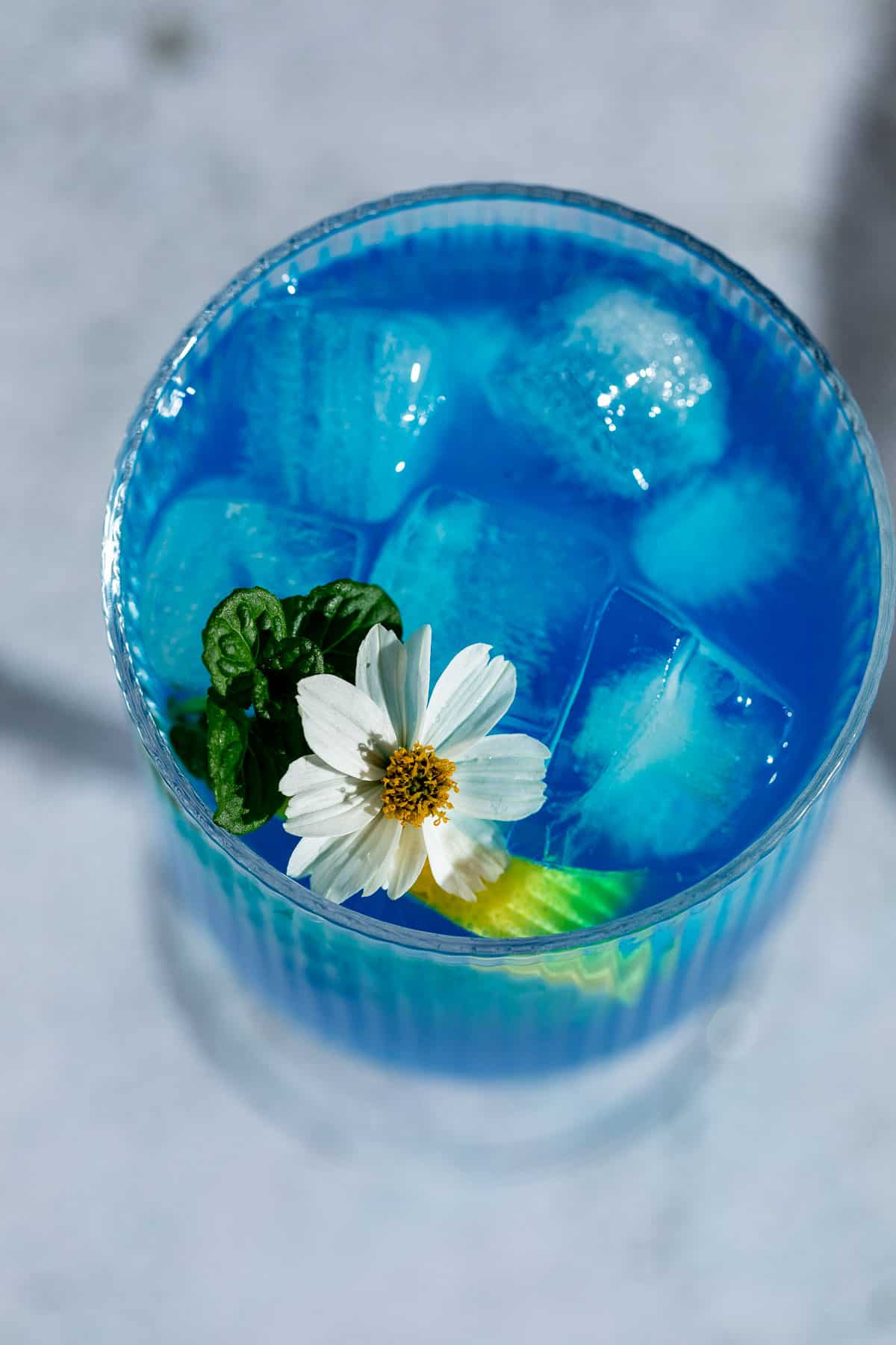 blue drink with ice and fresh white flower