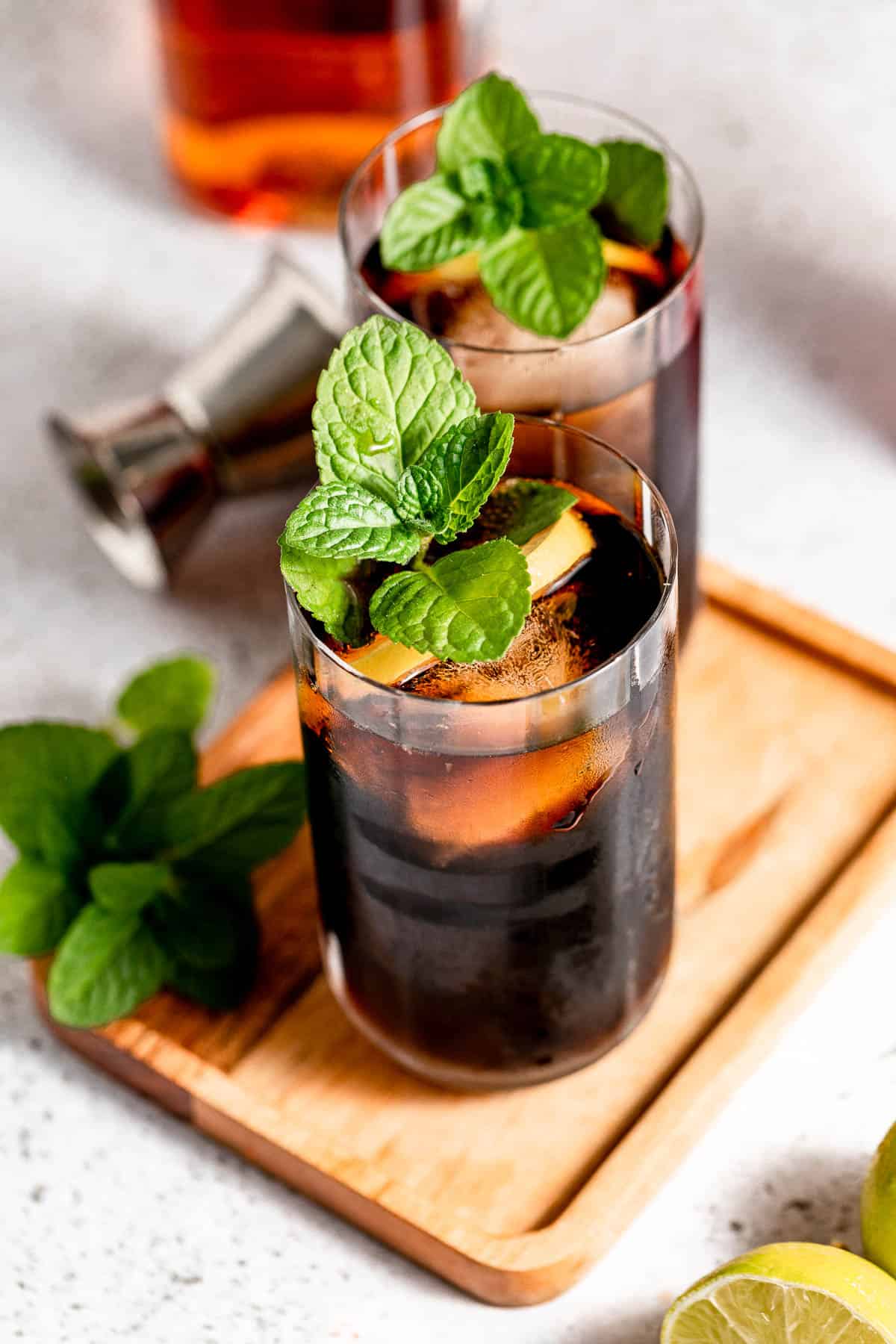 Rum and coke in two tall glasses garnished with fresh mint
