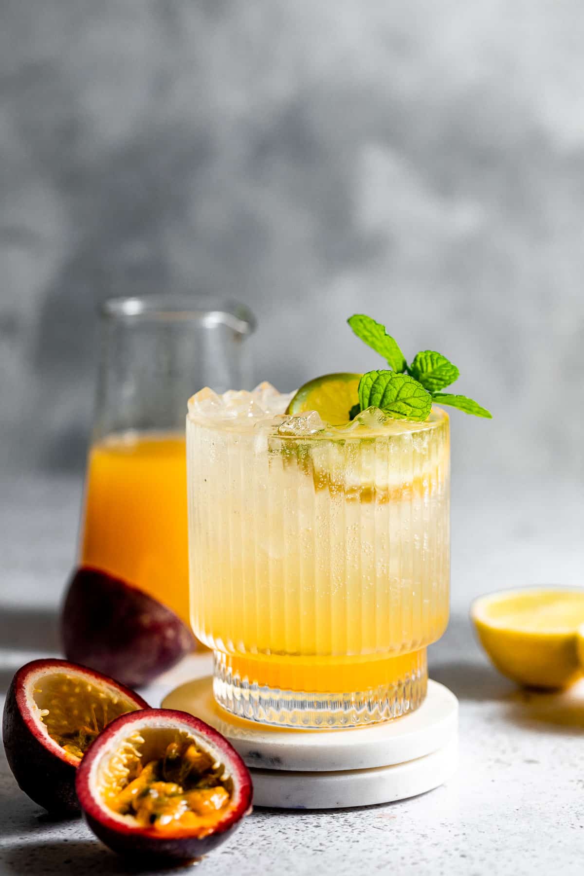 lemon vodka soda on marble coaster with fresh passionfruit halves