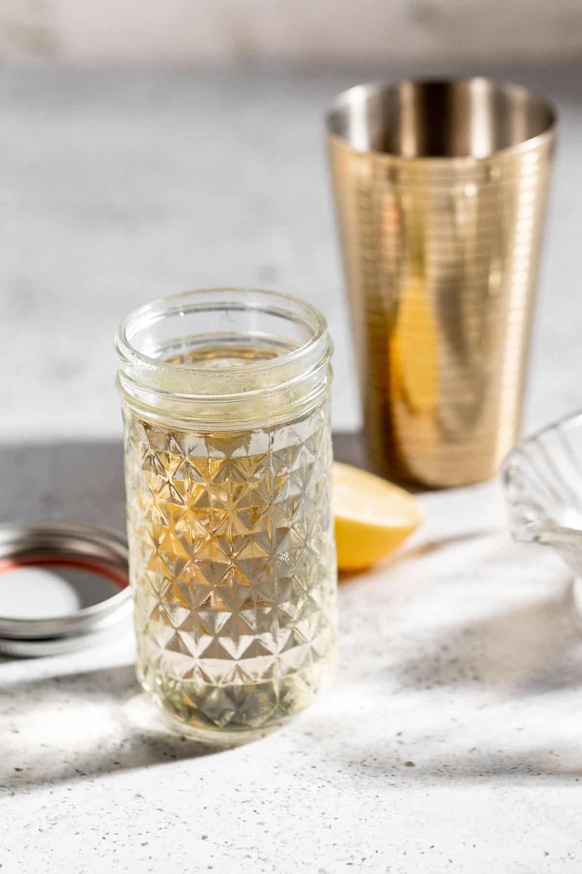 simple syrup in glass jar with gold cocktail shaker
