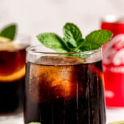 whiskey and coke in two short glasses topped with fresh mint