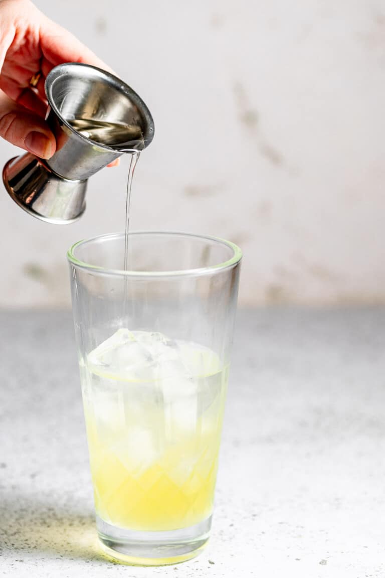 adding simple syrup to cocktail mixture