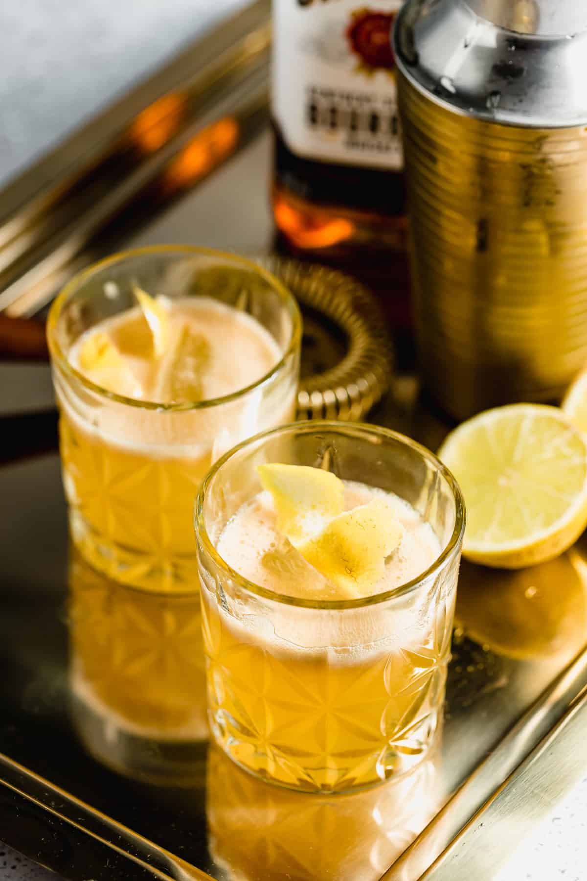 Two gold rush cocktails with fresh lemons.