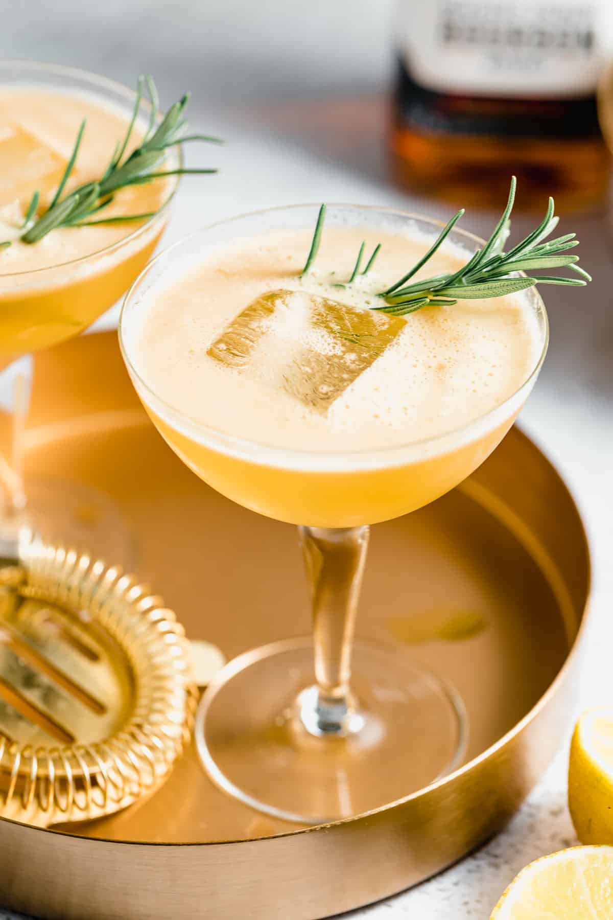 Two bourbon Smash cocktails served with ice on a gold tray.