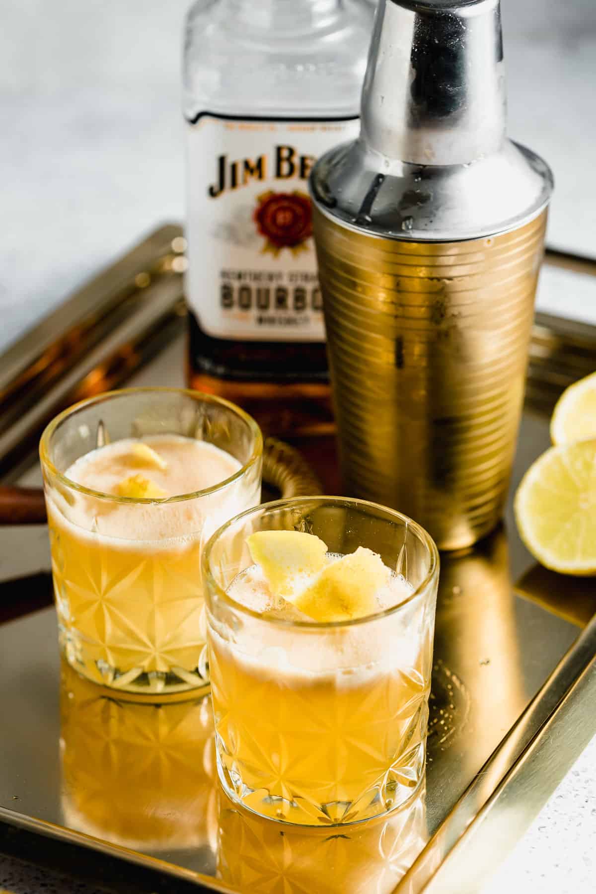 Two gold rush cocktails on a gold serving tray.