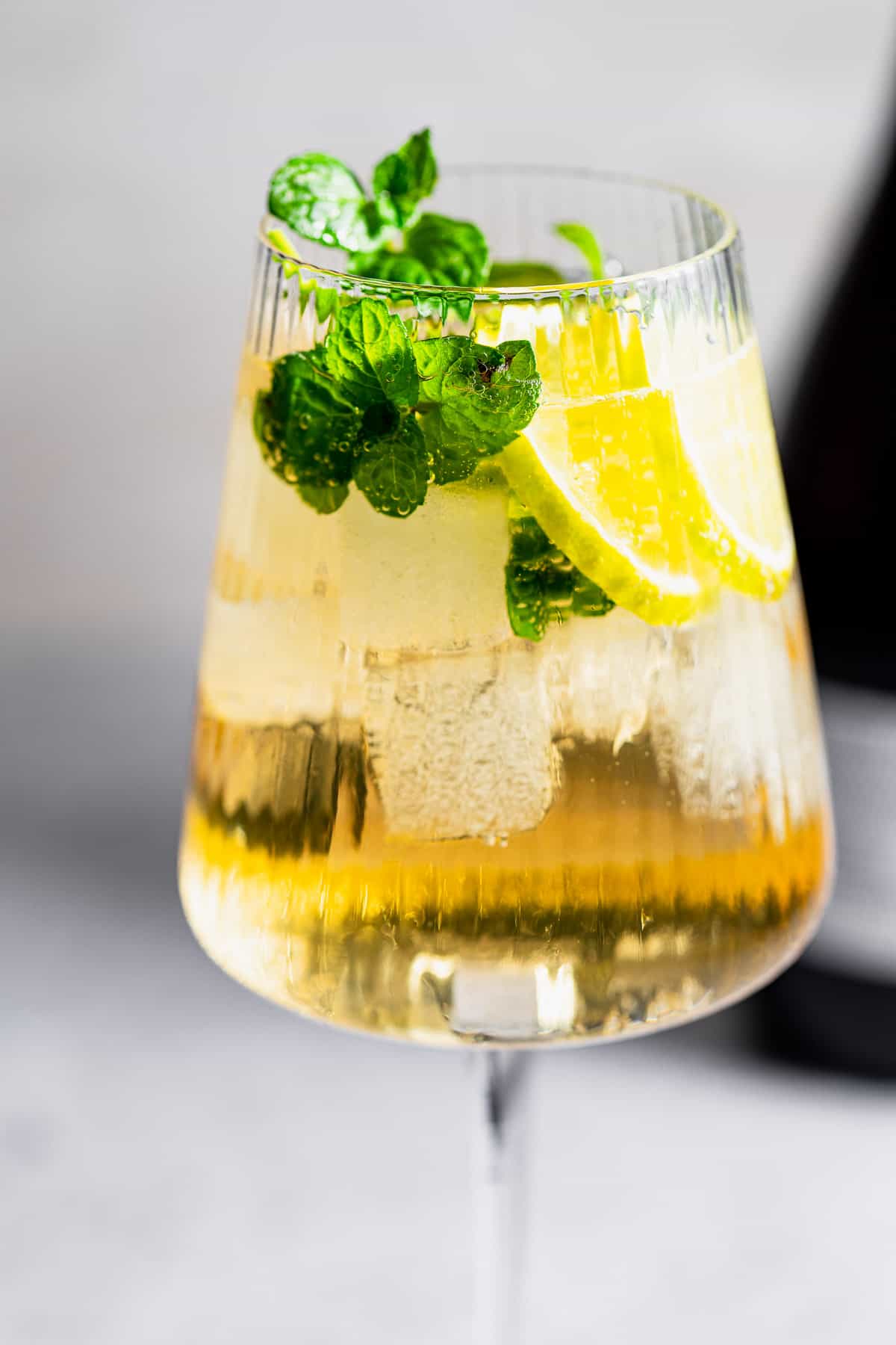 A Hugo Spritz cocktail with ice, mint, and lemon slices.