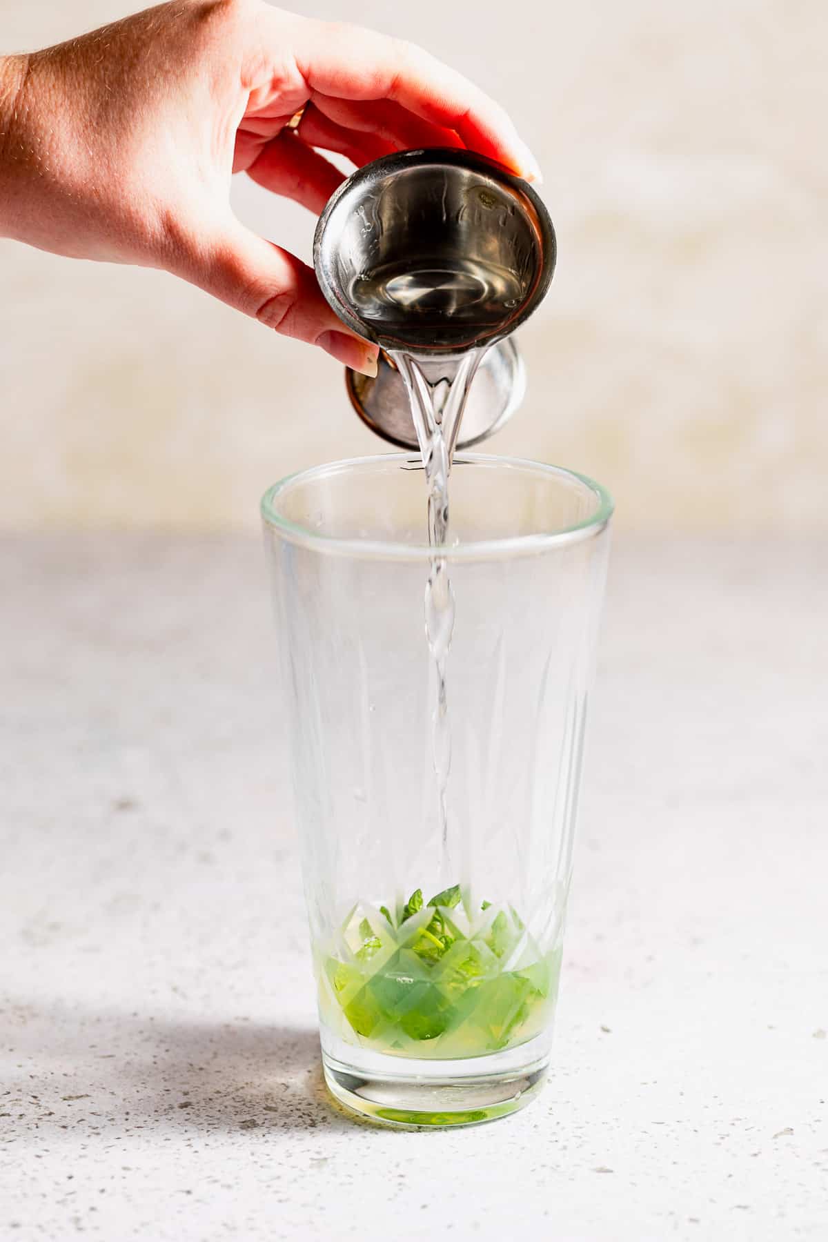 Simple syrup pouring into a glass drink shaker