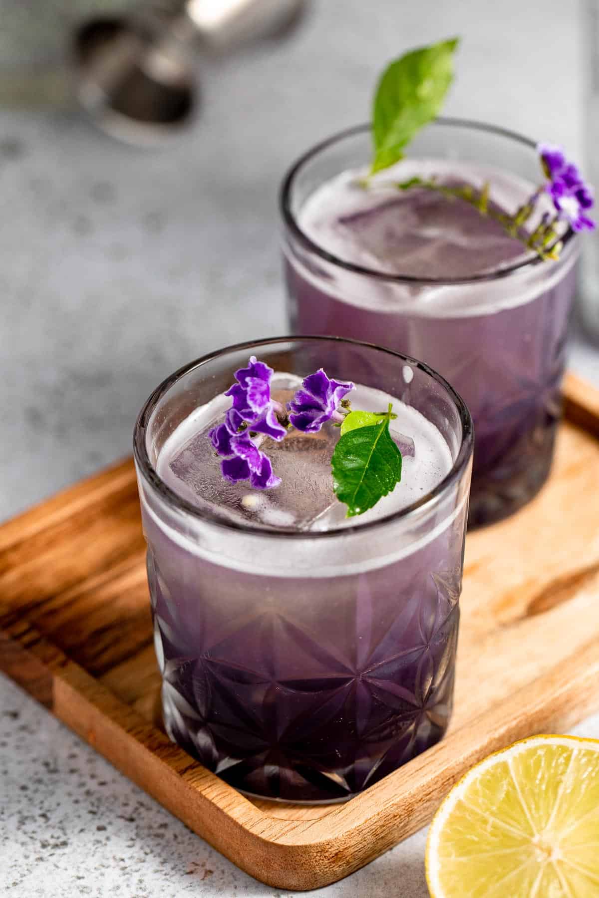 wooden tray topped with two glasses filled with purple rain cocktail