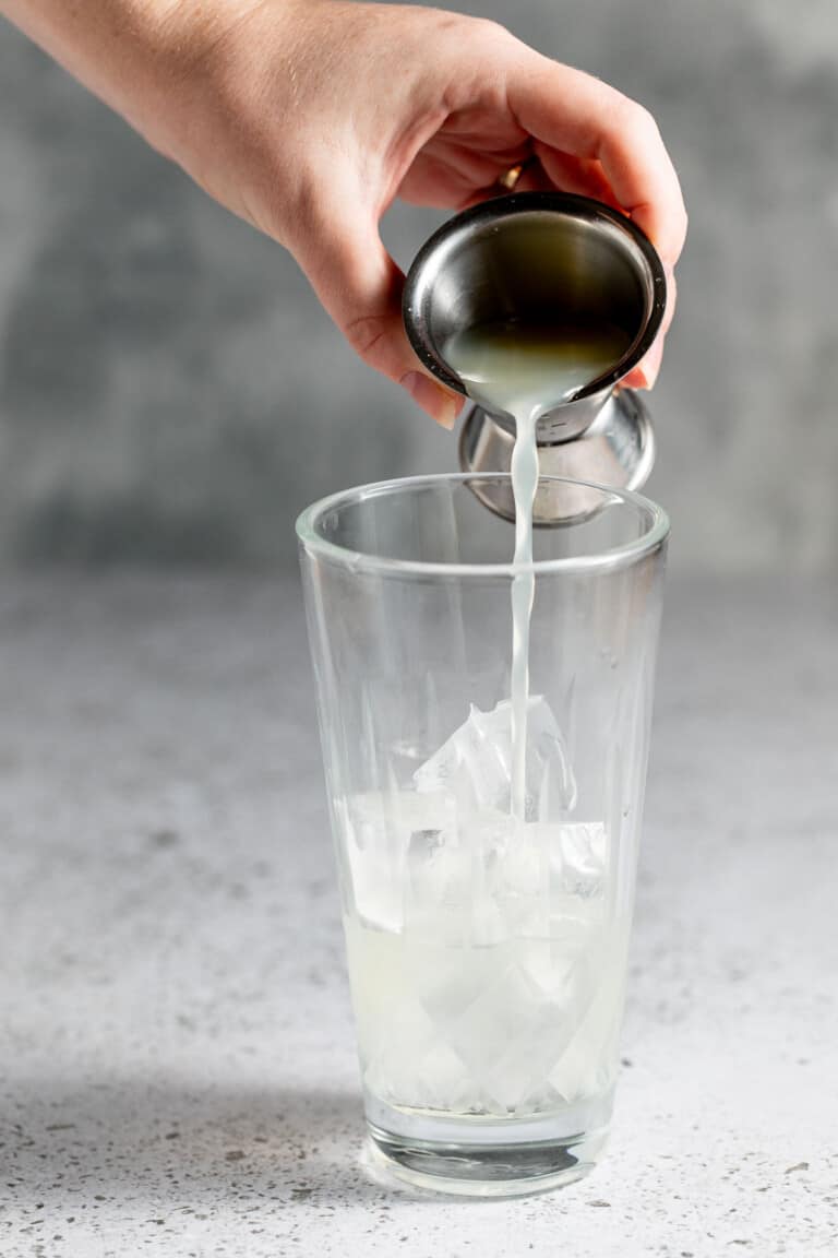 adding lemon juice with jigger into cocktail shaker