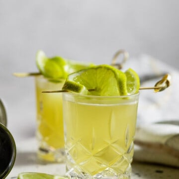 two shot glasses topped with lime slices